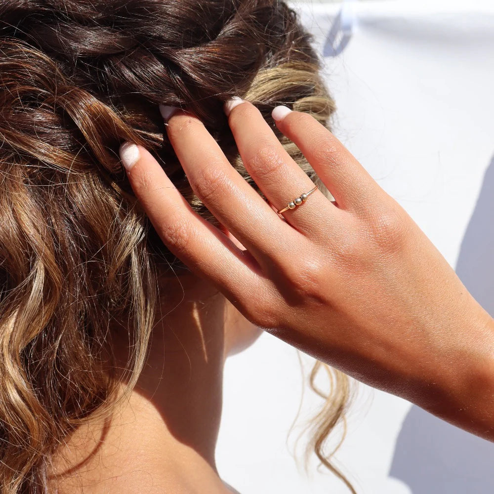 Token Jewelry Meridian Fidget Ring in gold worn on hand with hair styled in natural light.