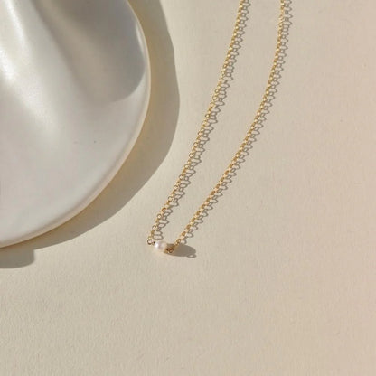 Flatlay of the Token Jewelry Mini Pearl Necklace showing delicate pearl detail.