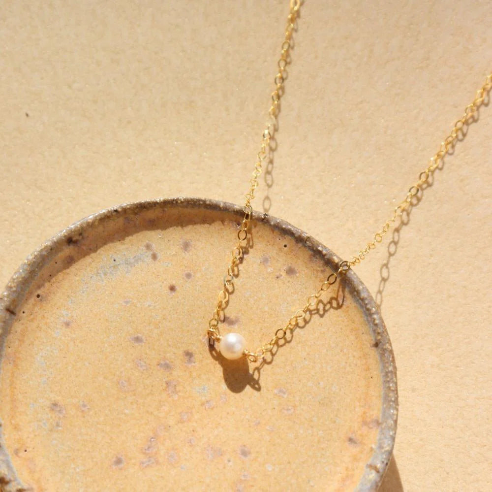 Token Jewelry Mini Pearl Necklace draped on a small textured dish.