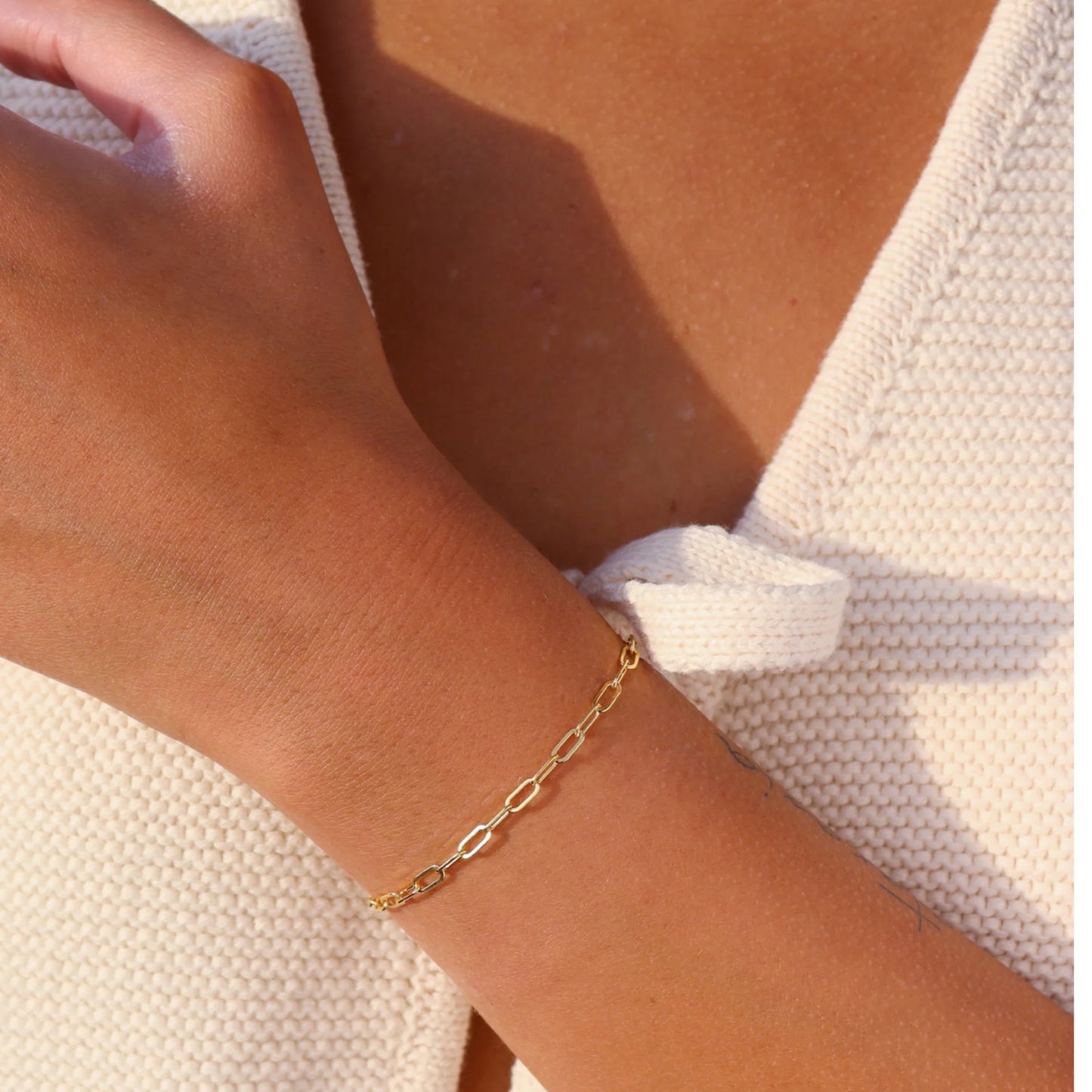 Token Jewelry Narrow Links Bracelet in gold styled with a white sweater featuring a bow detail.