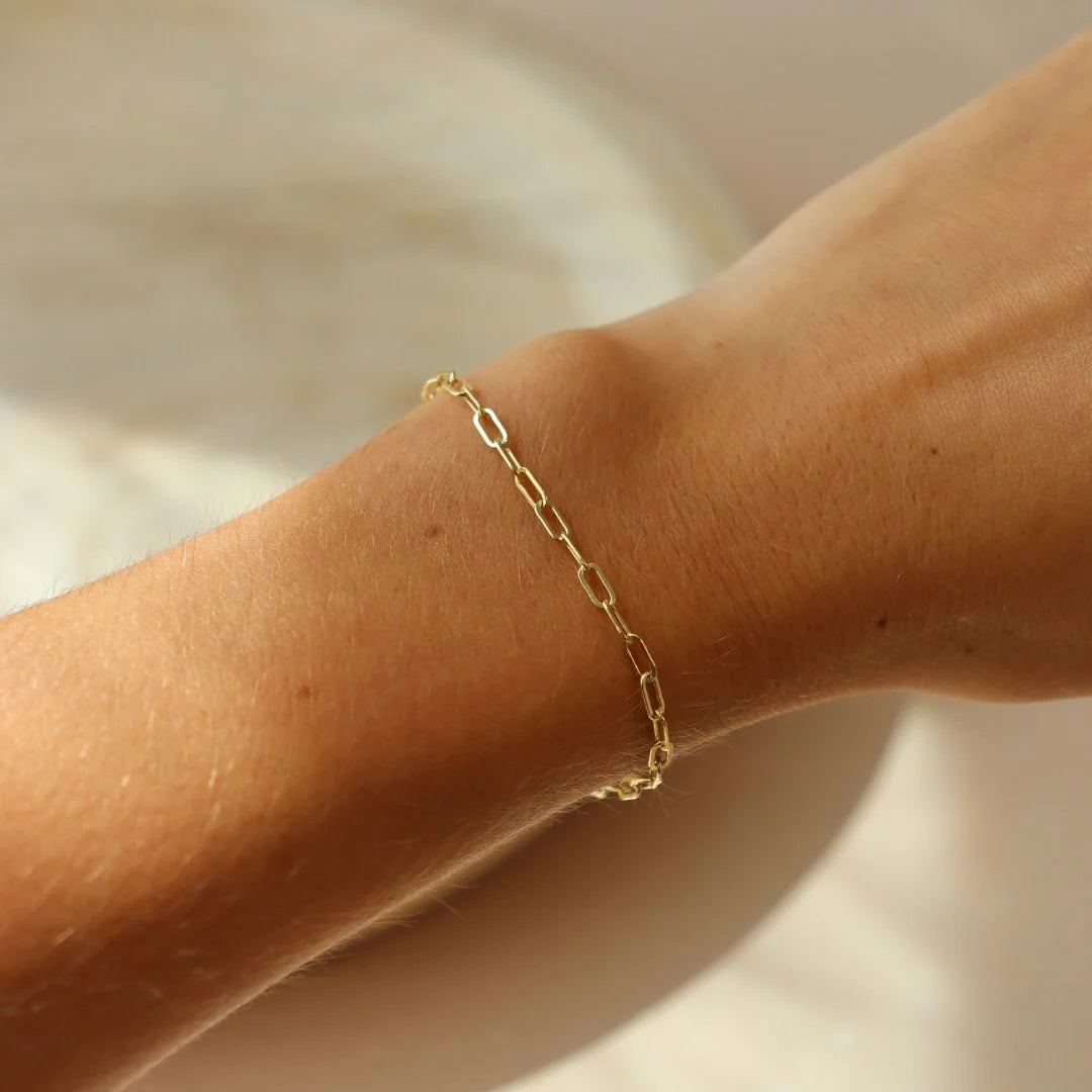 Closeup of Token Jewelry Narrow Links Bracelet in gold on wrist, styled with natural lighting.