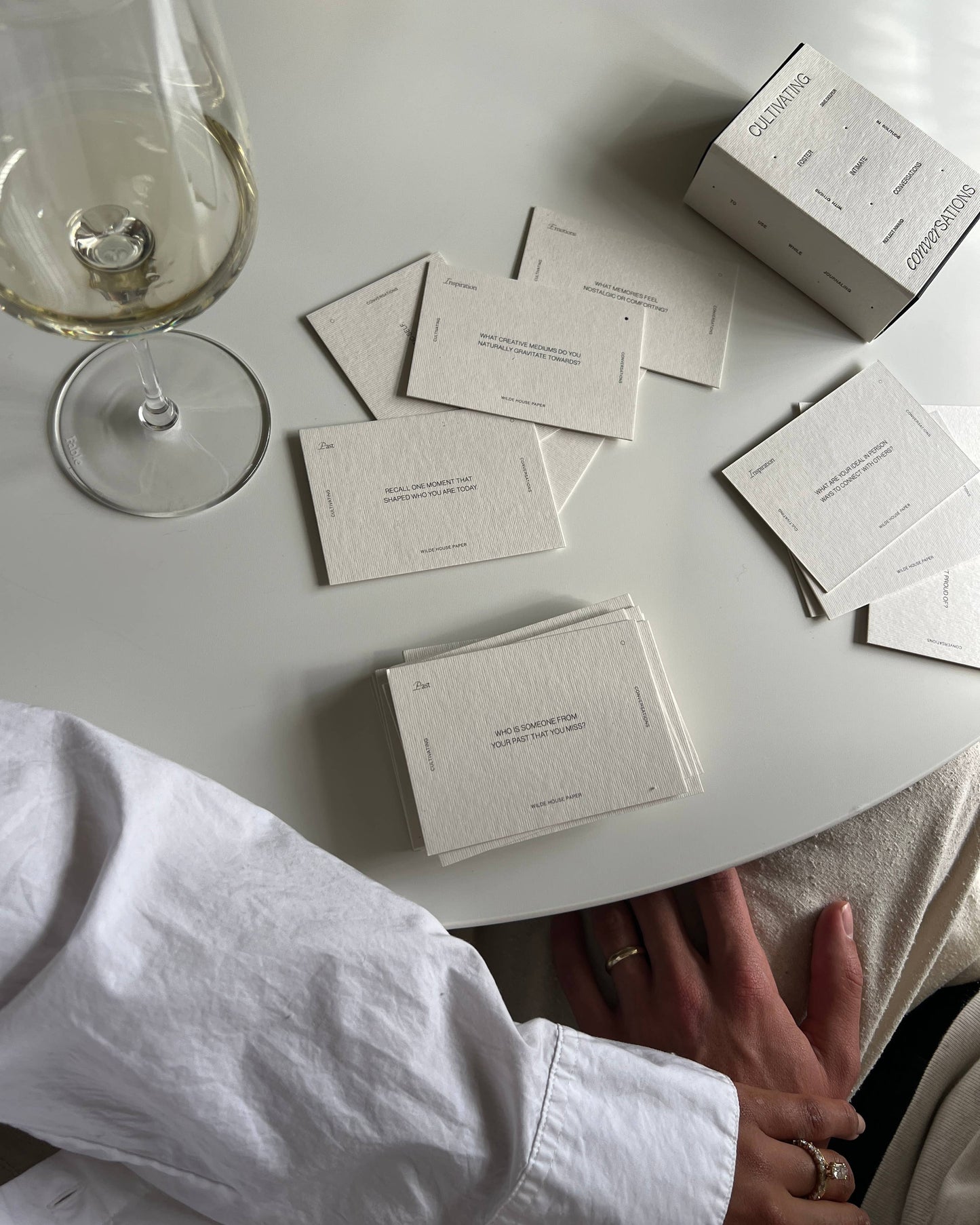 Wilde House Paper Cultivating Conversations cards spread out on table with two people seated.