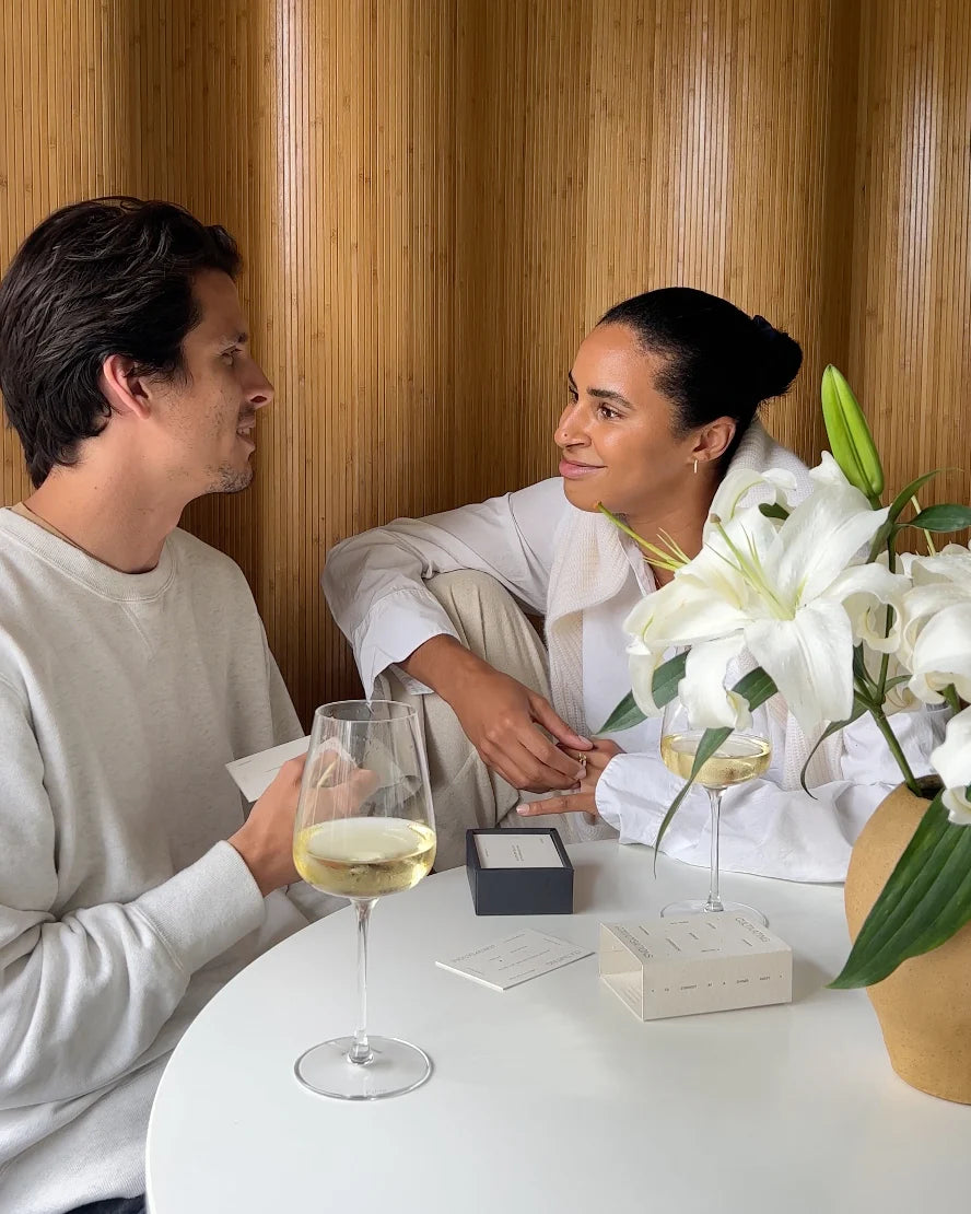 Couple smiling and playing Wilde House Paper Cultivating Conversations game at a cozy table.