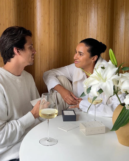 Couple smiling and playing Wilde House Paper Cultivating Conversations game at a cozy table.