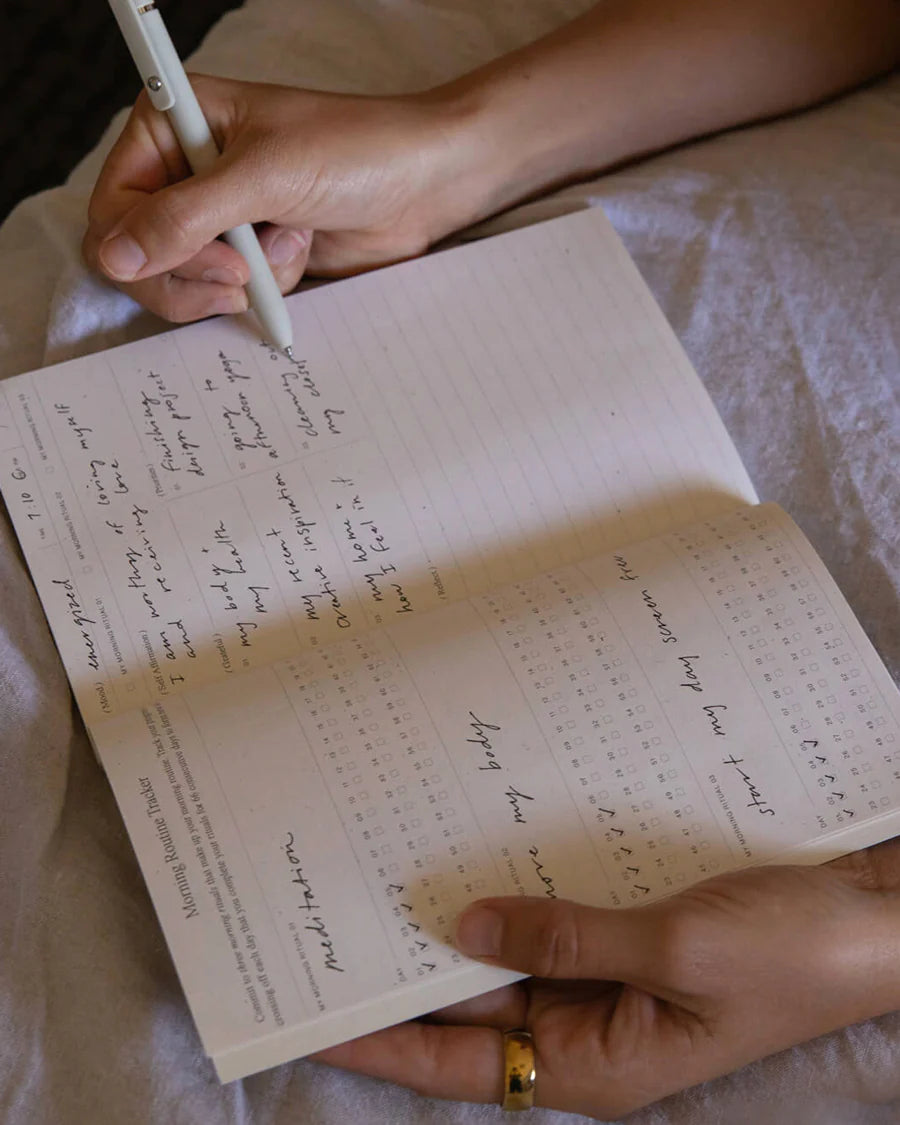 Hand writing in the Wilde House Paper Morning Routine Journal showing filled out morning tracker.