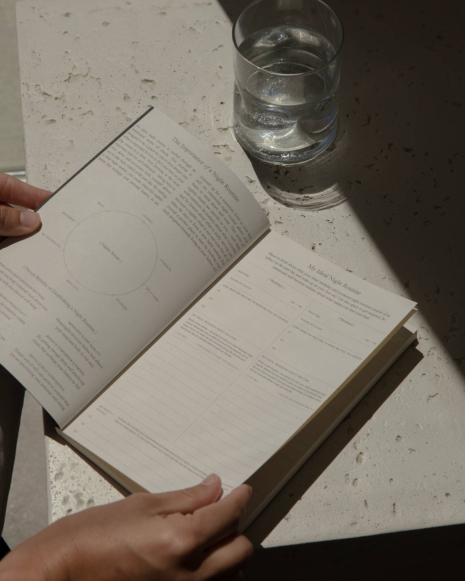 Person using the Wilde House Paper Night Routine Journal at a table with water glass.