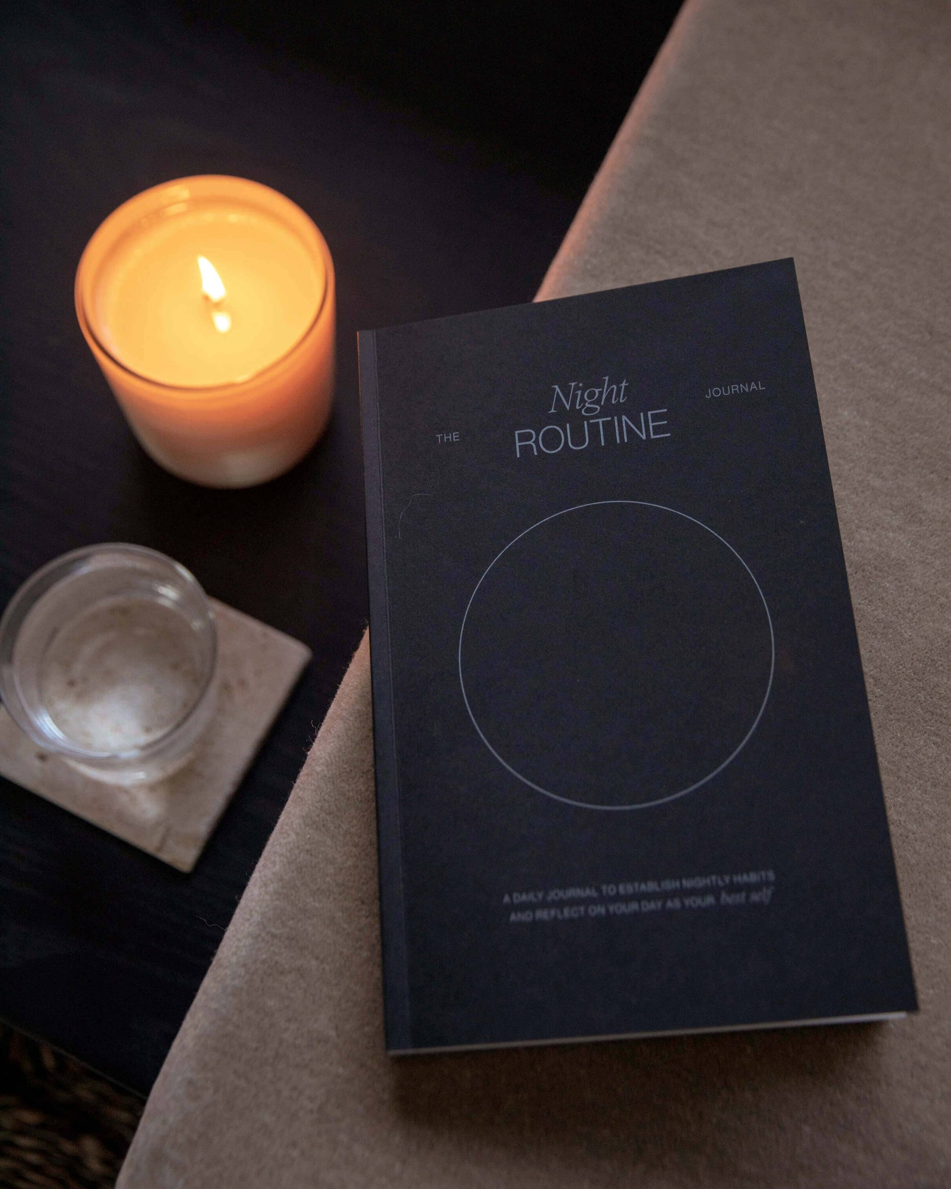 Wilde House Paper Night Routine Journal placed on a table beside a lit candle.
