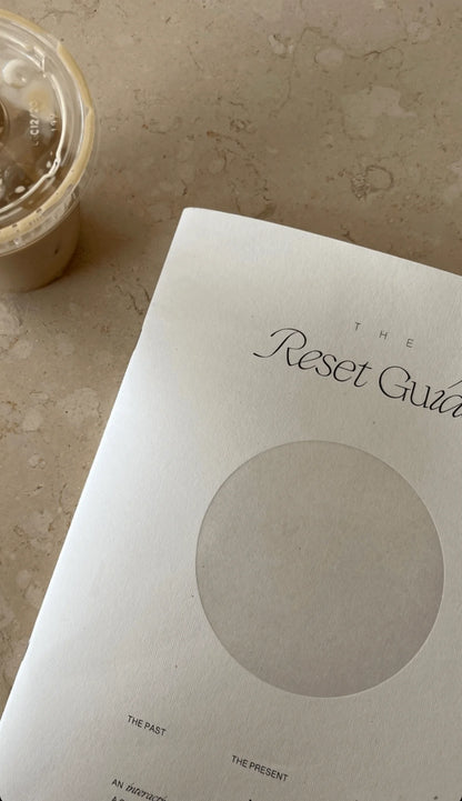 The Reset Guide by Wilde House Paper placed on a coffee table next to an iced coffee cup.
