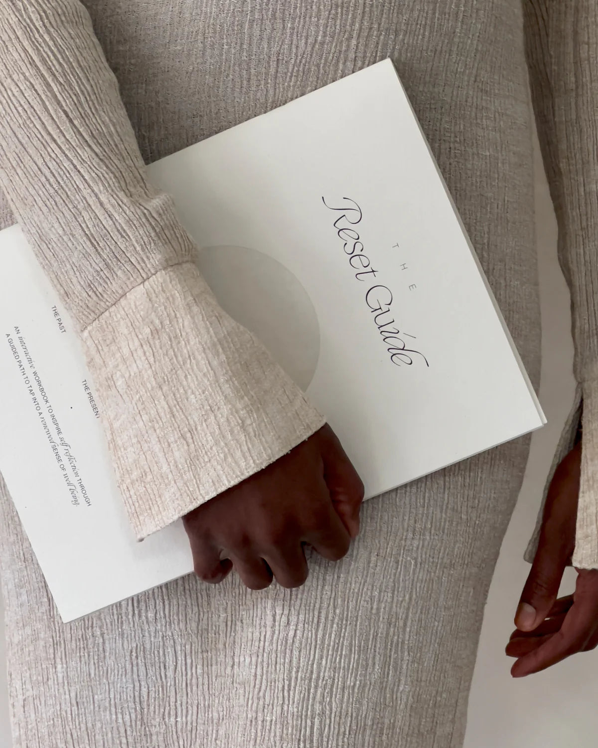 Person holding The Reset Guide by Wilde House Paper while wearing a soft elegant outfit.