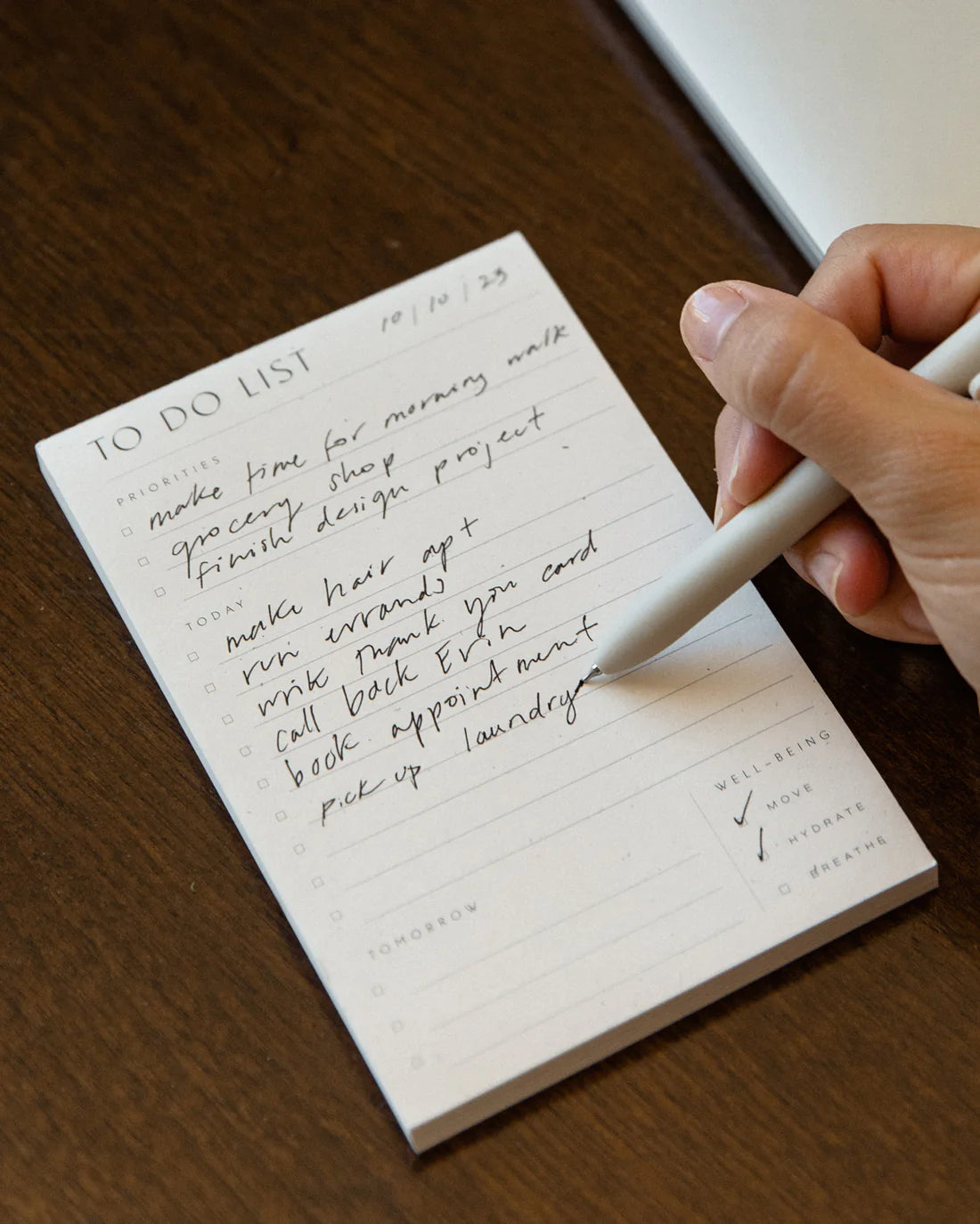 Wilde House Paper To Do List Pad in use, with handwritten tasks and a pen writing. 
