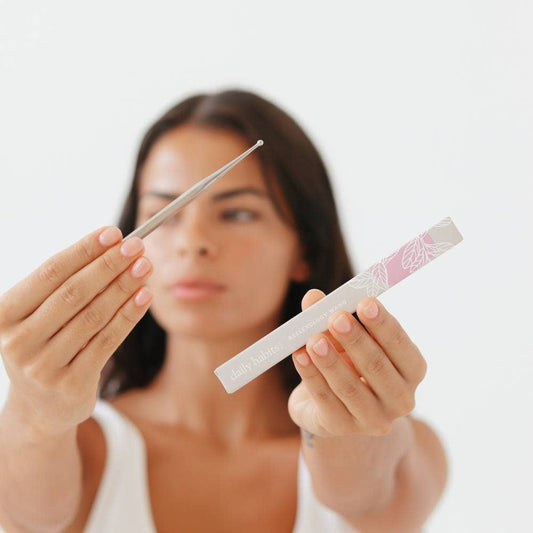 Woman holding Daily Habits Facial Reflexology Tool with pink and grey packaging.