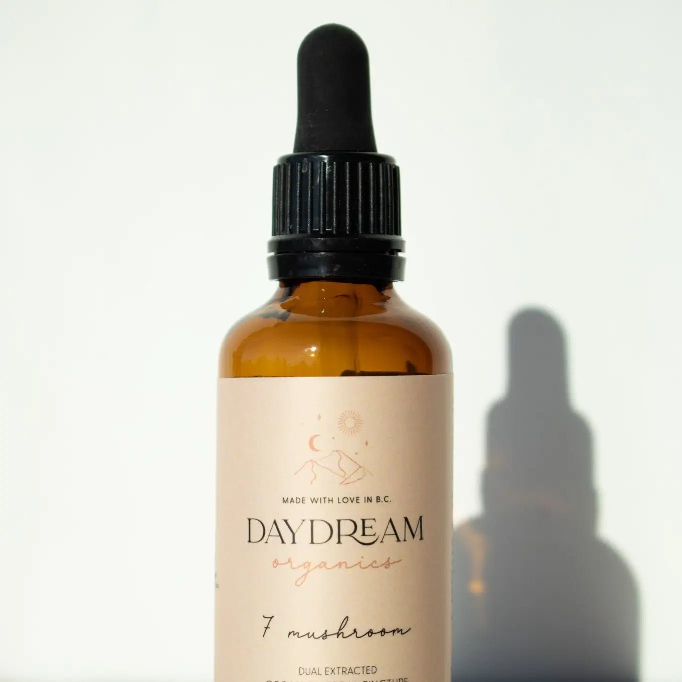 Daydream Organics Seven Mushroom Blend Tincture bottle casting a shadow on a white background.