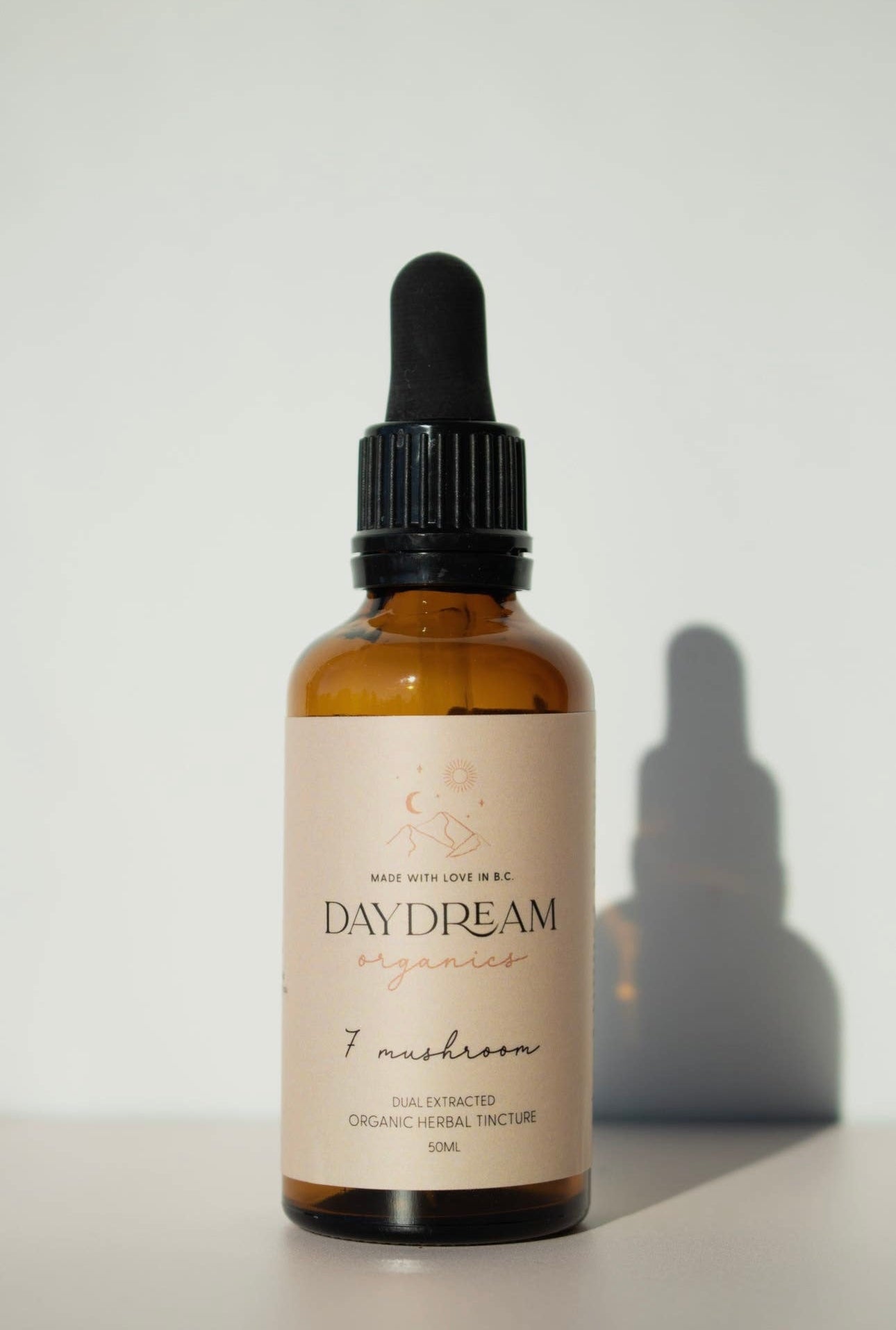 Close-up of Daydream Organics Seven Mushroom Blend Tincture bottle on a sunlit surface.