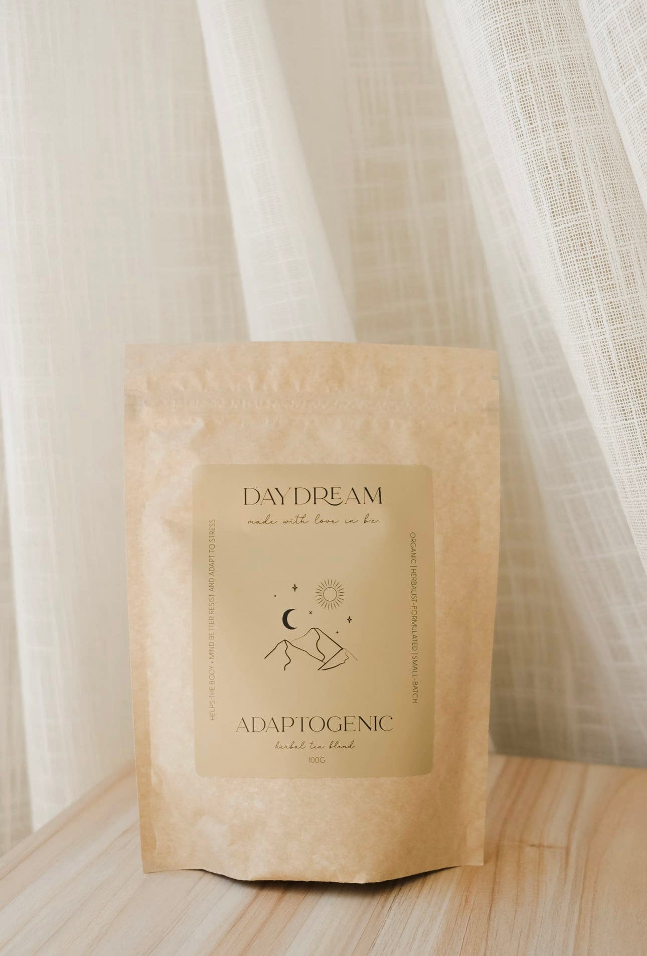 Daydream Organics Adaptogenic Herbal Tea bag standing on a wooden surface with soft curtain backdrop.