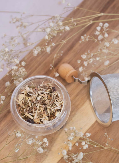 Loose leaf blend of Daydream Organics Adaptogenic Herbal Tea with infuser placed on a wooden board.
