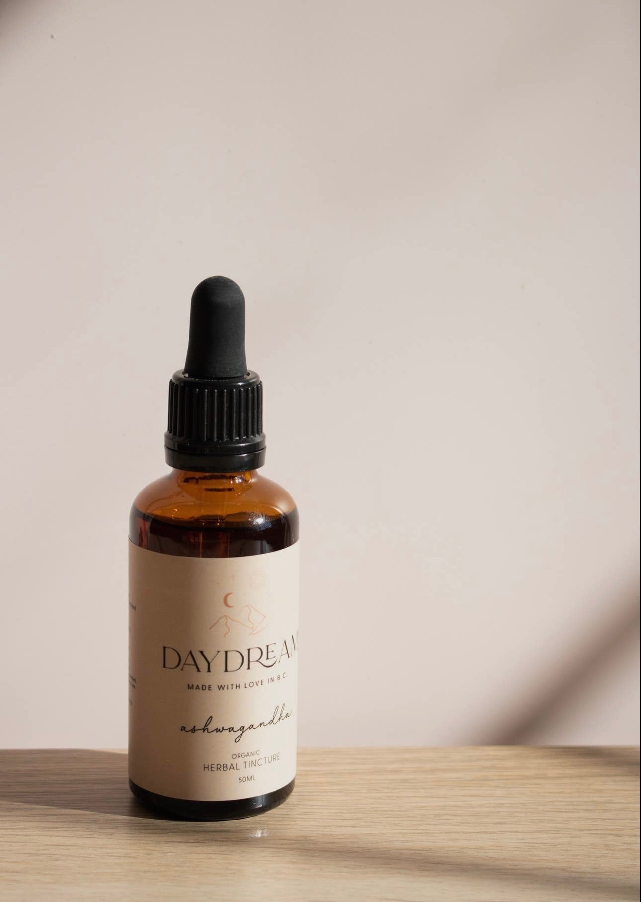 Close-up of Daydream Organics Ashwagandha Herbal Tincture bottle on a wooden table with natural lighting.