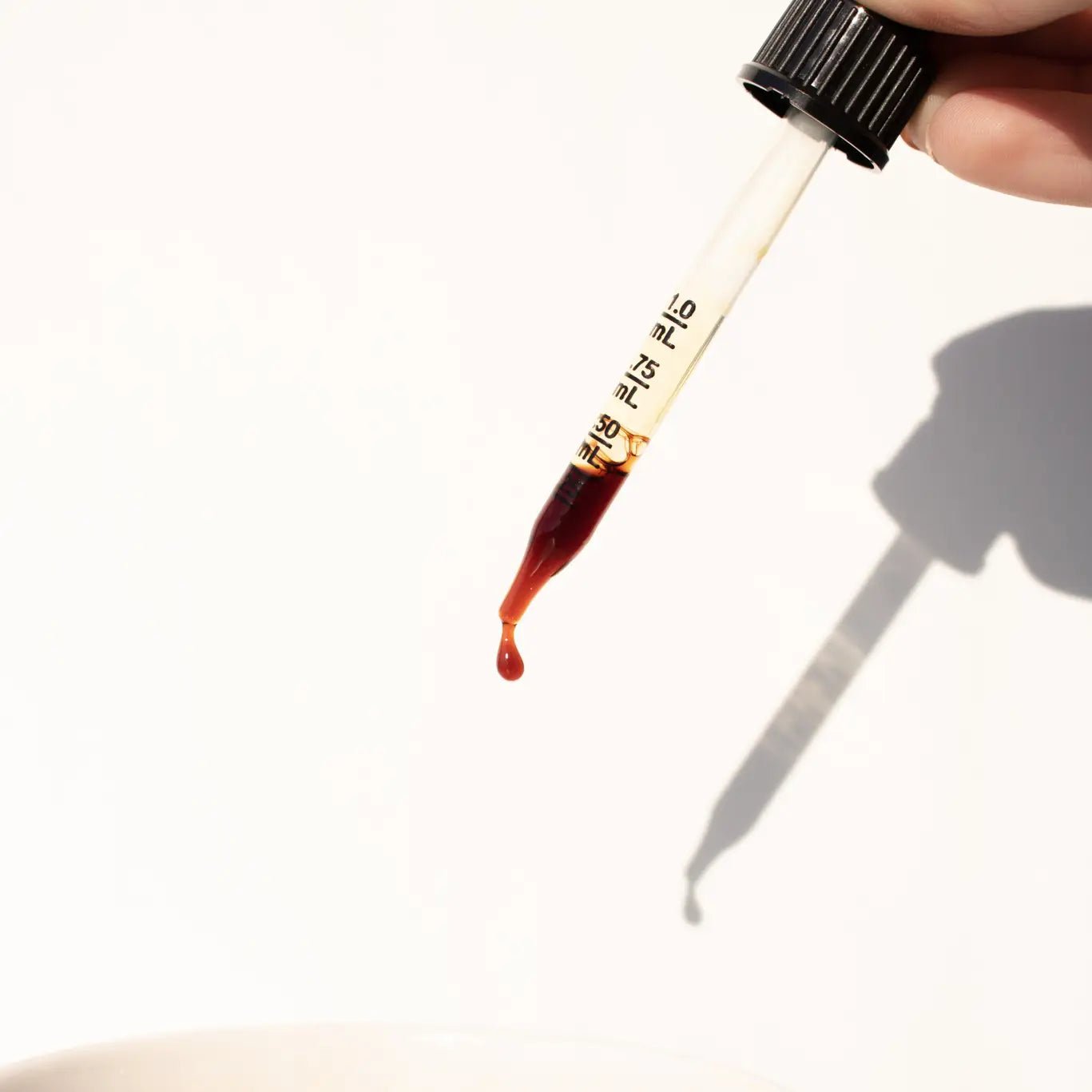 Close-up of herbalntincture dropper releasing golden liquid by Daydream Organics.