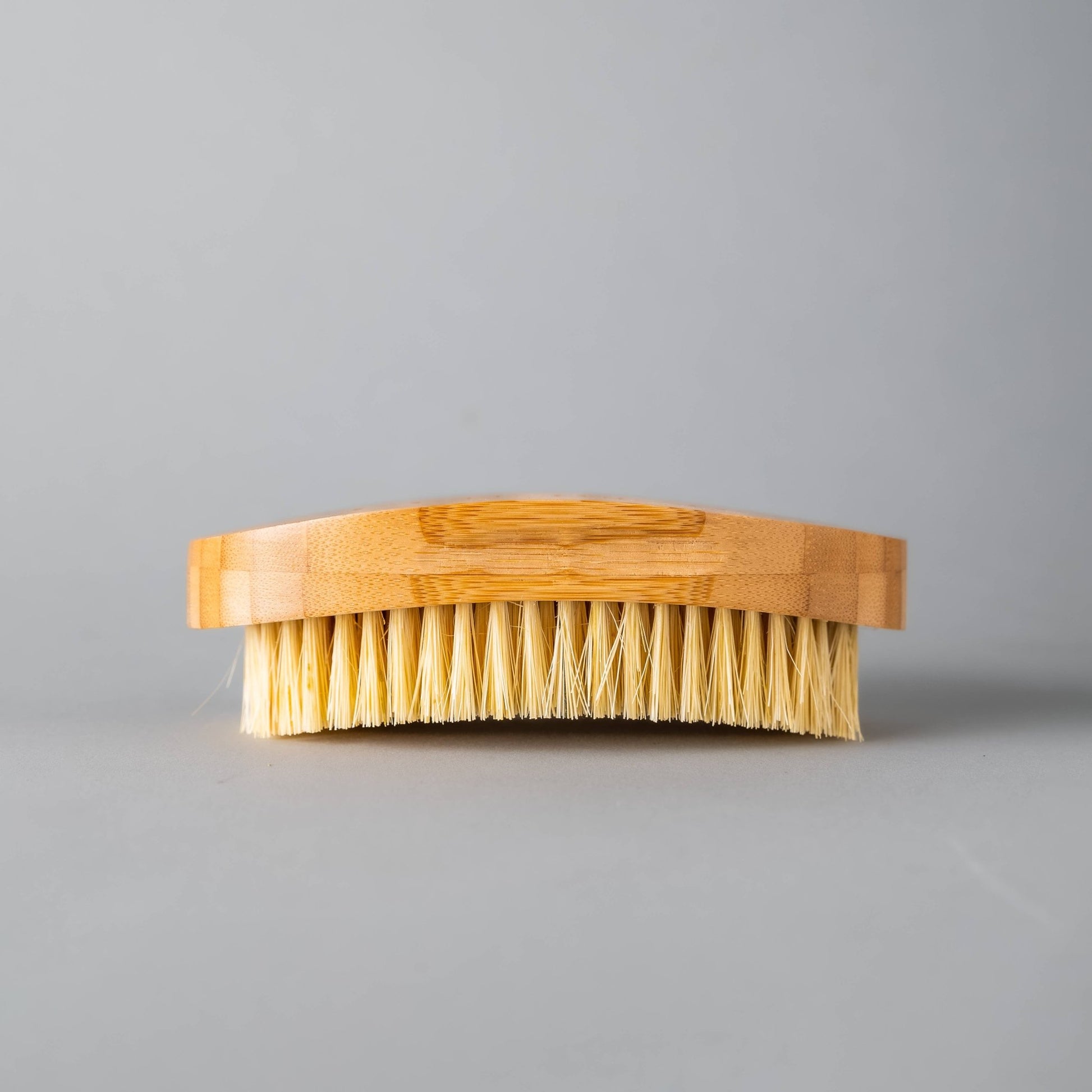 Side profile of detoxifying dry body brush showcasing natural bristles and ergonomic bamboo handle.