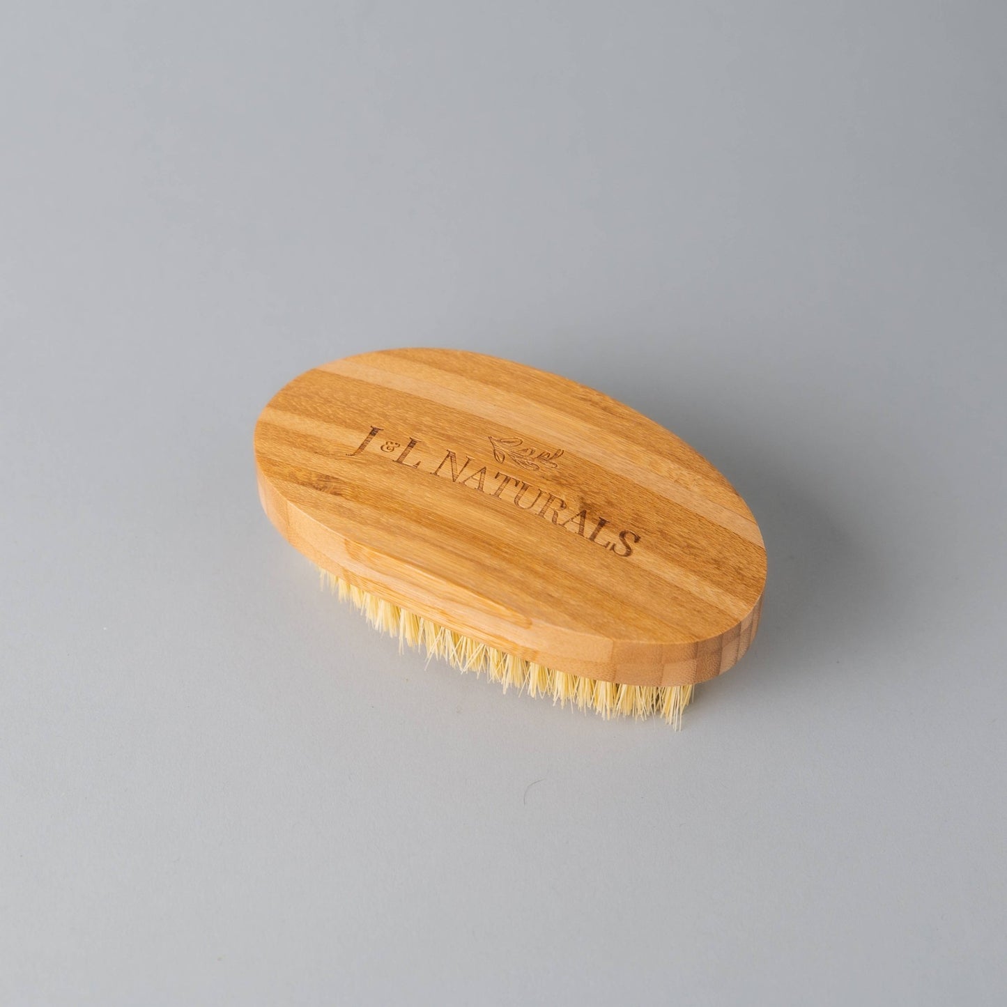 Top view of detoxifying dry body brush featuring bamboo handle and engraved logo.