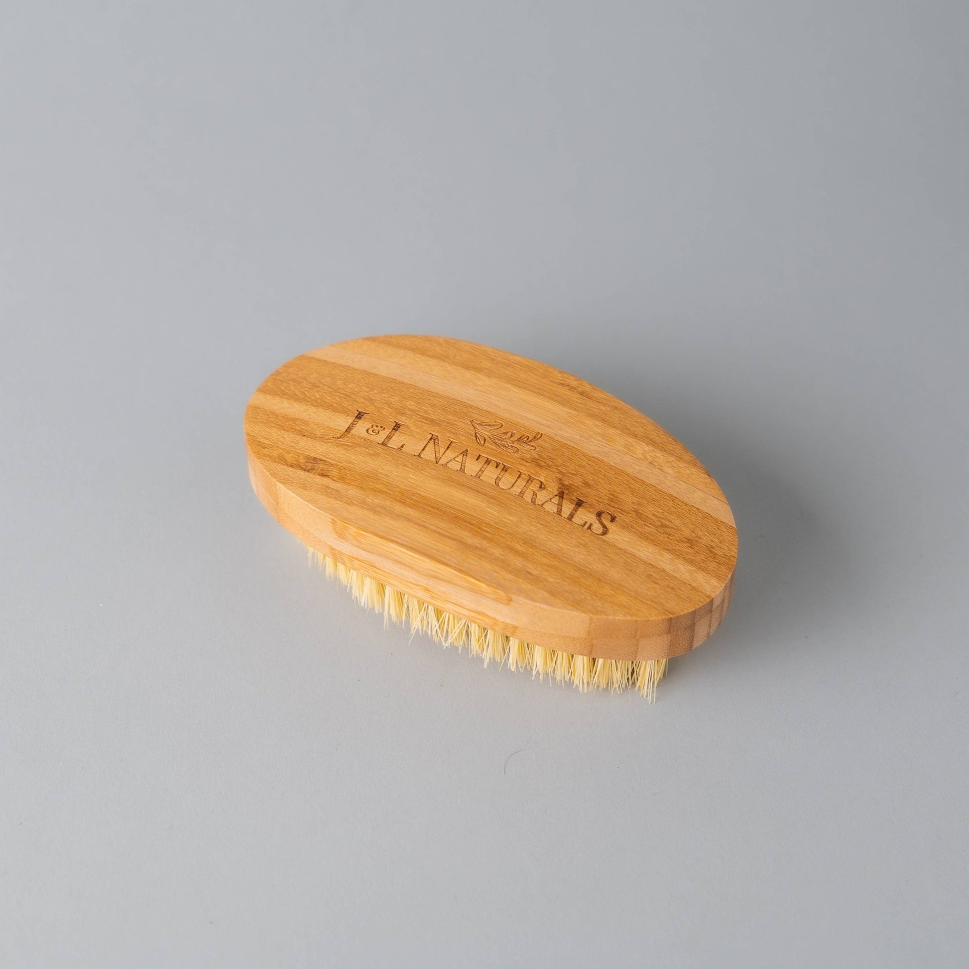 Top view of detoxifying dry body brush featuring bamboo handle and engraved logo.