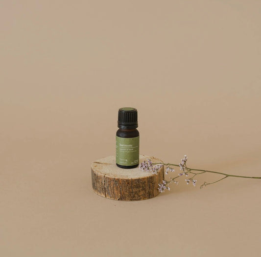 Fern & Petal Harmony Essential Oil bottle displayed on a wood slice with delicate flowers and neutral background.
