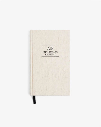 The Five Minute Journal with linen cover laid flat on white background, showcasing minimalist design.