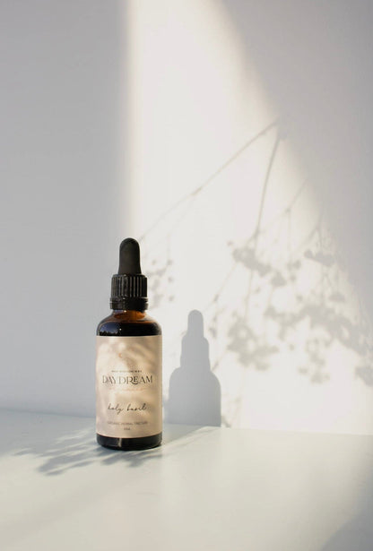 Daydream Organics Holy Basil Tulsi Tincture with floral shadows.