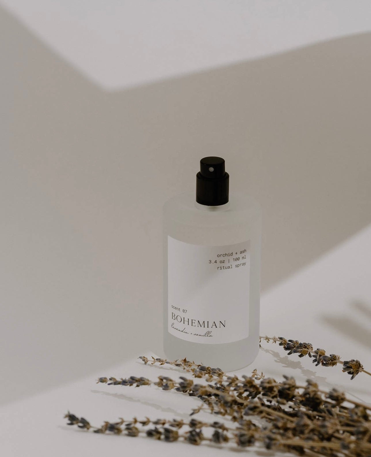 Orchid & Ash Bohemian spray with lavender sprigs casting shadows on a minimal background.