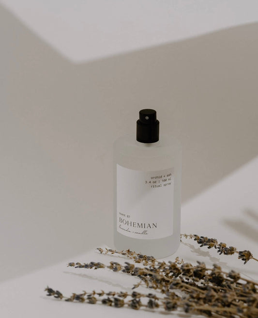 Orchid & Ash Bohemian spray with lavender sprigs casting shadows on a minimal background.