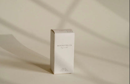 Minimalist packaging of Orchid & Ash room linen spray bathed in soft shadowed light.