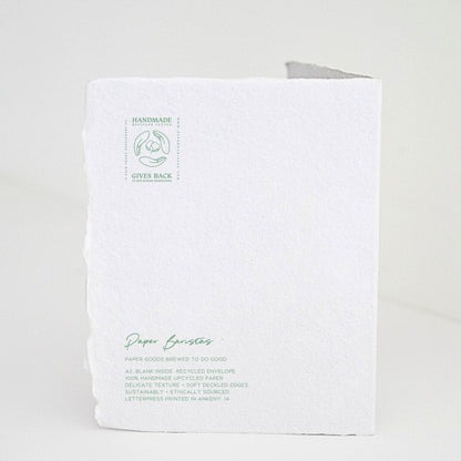 Back of Paper Baristas holiday "With Love and Peace" greeting card with letterpress details and ethical production message in green ink.