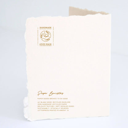 Back of Paper Baristas "Your Love Story Is One For The Ages, Cheers" greeting card with letterpress details and ethical production message.