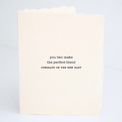 Front of Paper Baristas baby greeting card reading “You Two Make The Perfect Blend — Congrats On The New Baby” on textured cotton recycled paper in black ink.