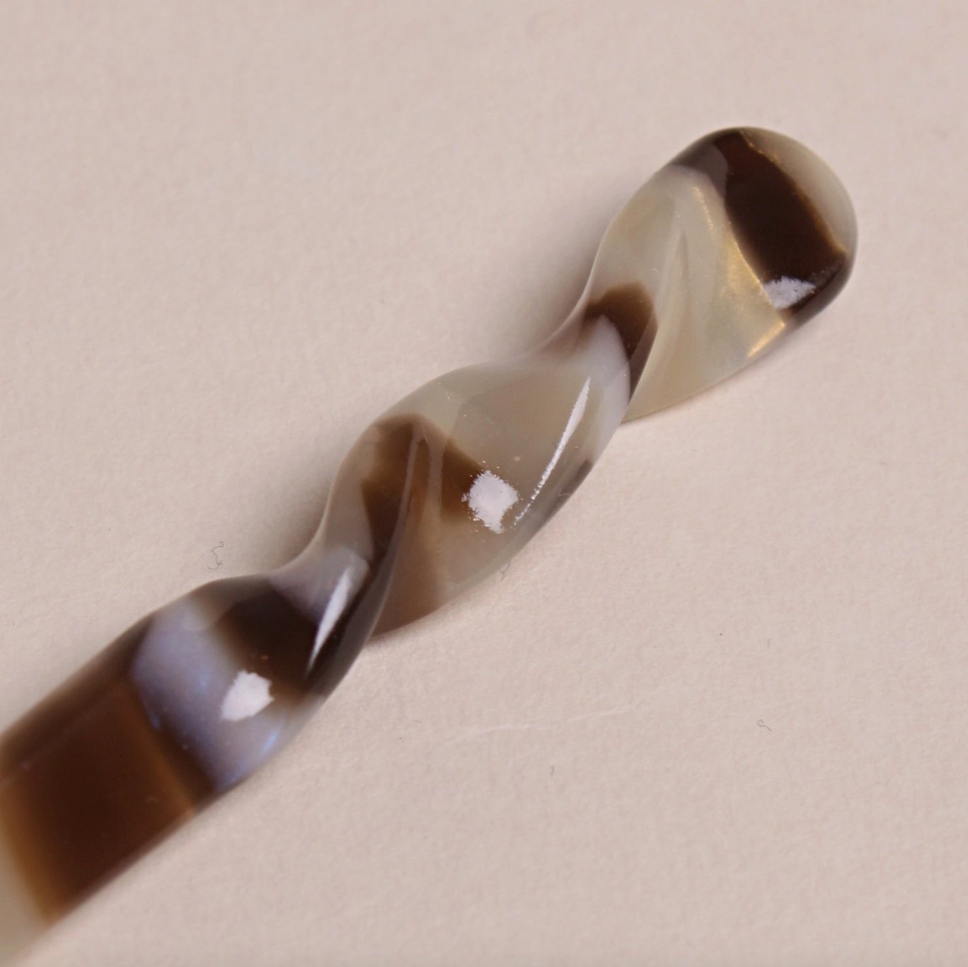 Close-up view of mocha swirl Peignée Paris acetate hair stick pin.