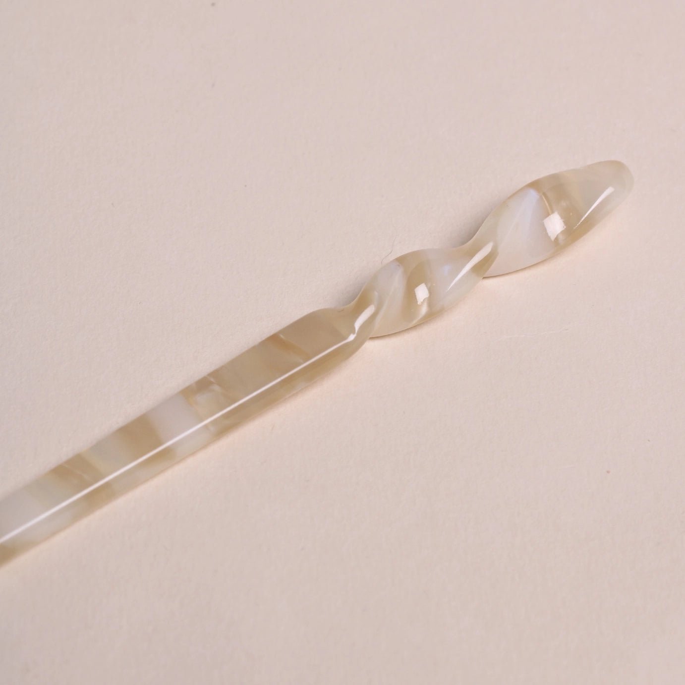 Close-up details of ivory colored swirl of Peignée Paris acetate hair stick pin in popcorn.