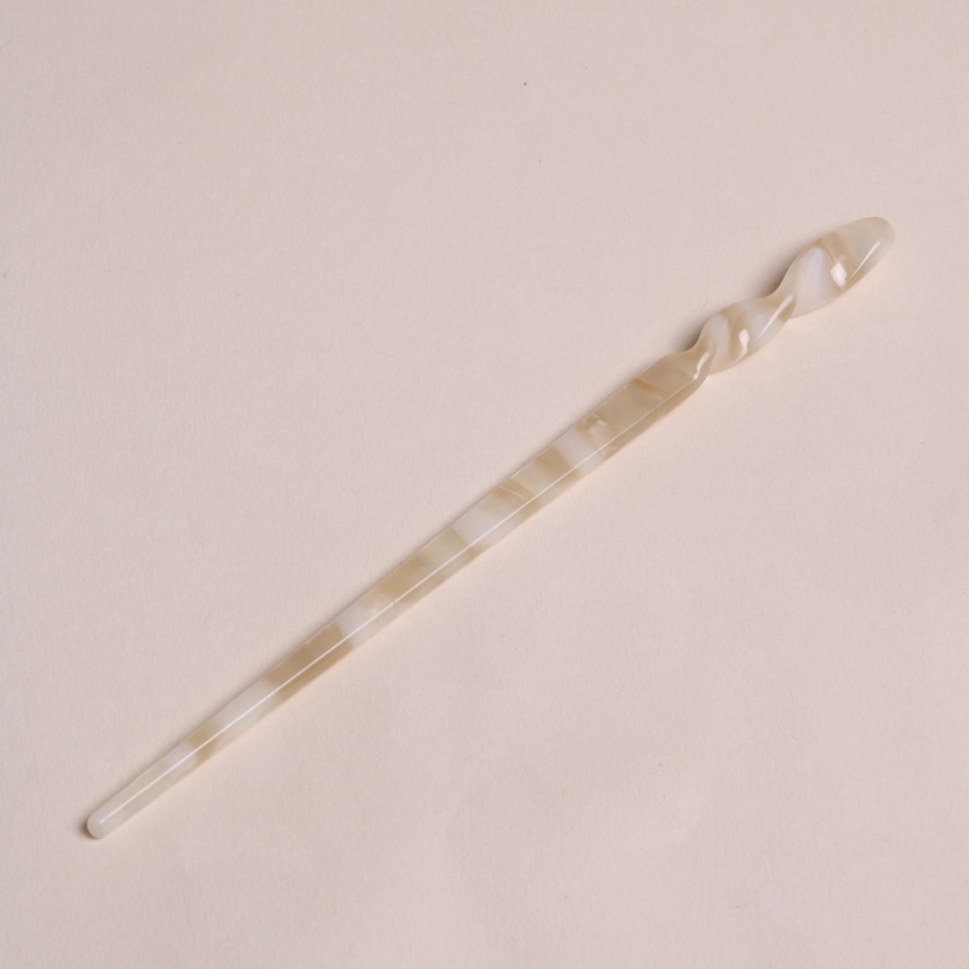 Ivory-toned Peignée Paris acetate hair stick pin in popcorn shade laying flat on neutral background.