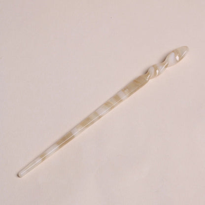 Ivory-toned Peignée Paris acetate hair stick pin in popcorn shade laying flat on neutral background.