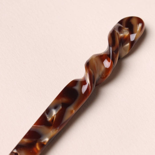 Close-up of the twisted details of the espresso colored Peignée Paris hair stick pin on neutral background.