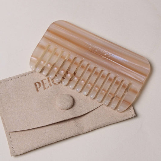 Peignée Paris travel comb in Latte resting on beige suede storage pouch.