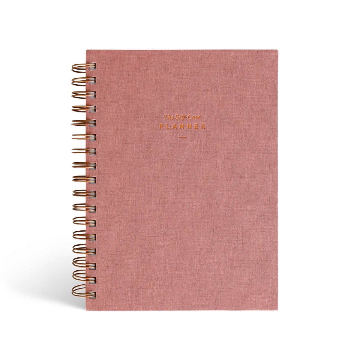 The Self Care Planner Weekly Edition in dusty rose color, front cover with gold foil text.