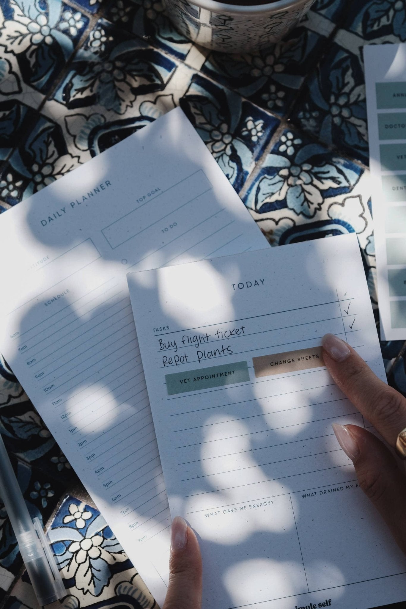 Simple Self Co Work Sticker Set applied to a daily planner in an outdoor setting with dappled sunlight.