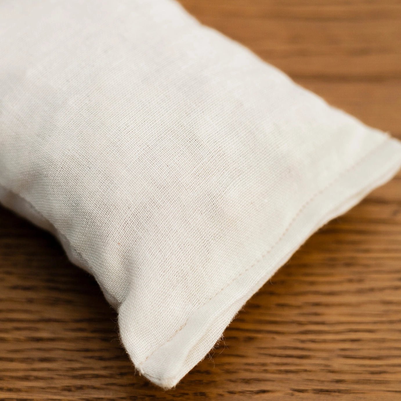 A close-up of the Cedar Sachet’s natural cotton fabric, highlighting its clean stitching and texture on a wooden background.