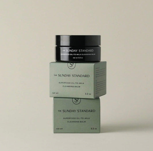 Product image of The Sunday Standard Superfood Oil-to-Milk Cleansing Balm, jar stacked on boxes.