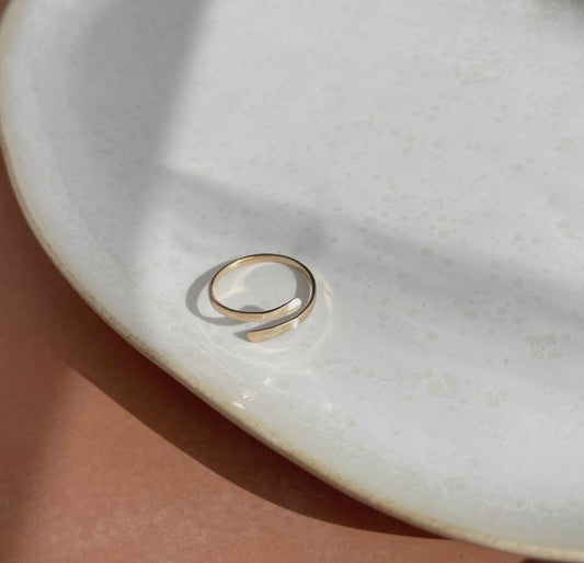 Token Jewelry Coil Ring in gold displayed on a white ceramic plate.