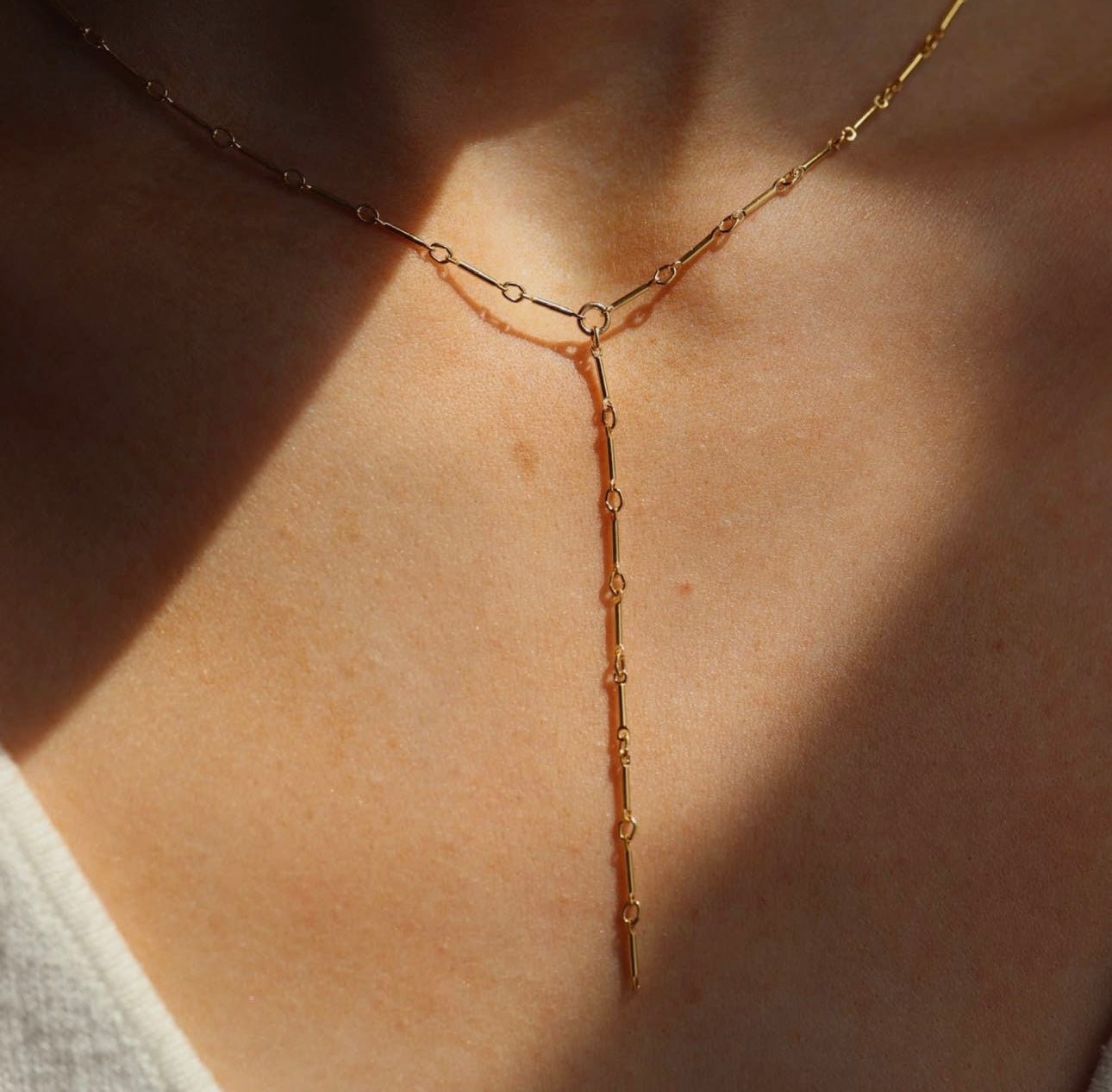 Model wearing Token Jewelry Dot and Dash Lariat necklace in gold with natural lighting