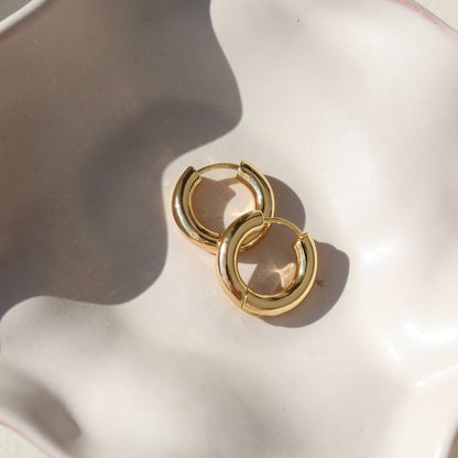 Token Jewelry Everyday Hoops gold earrings stacked together on a curved white dish.