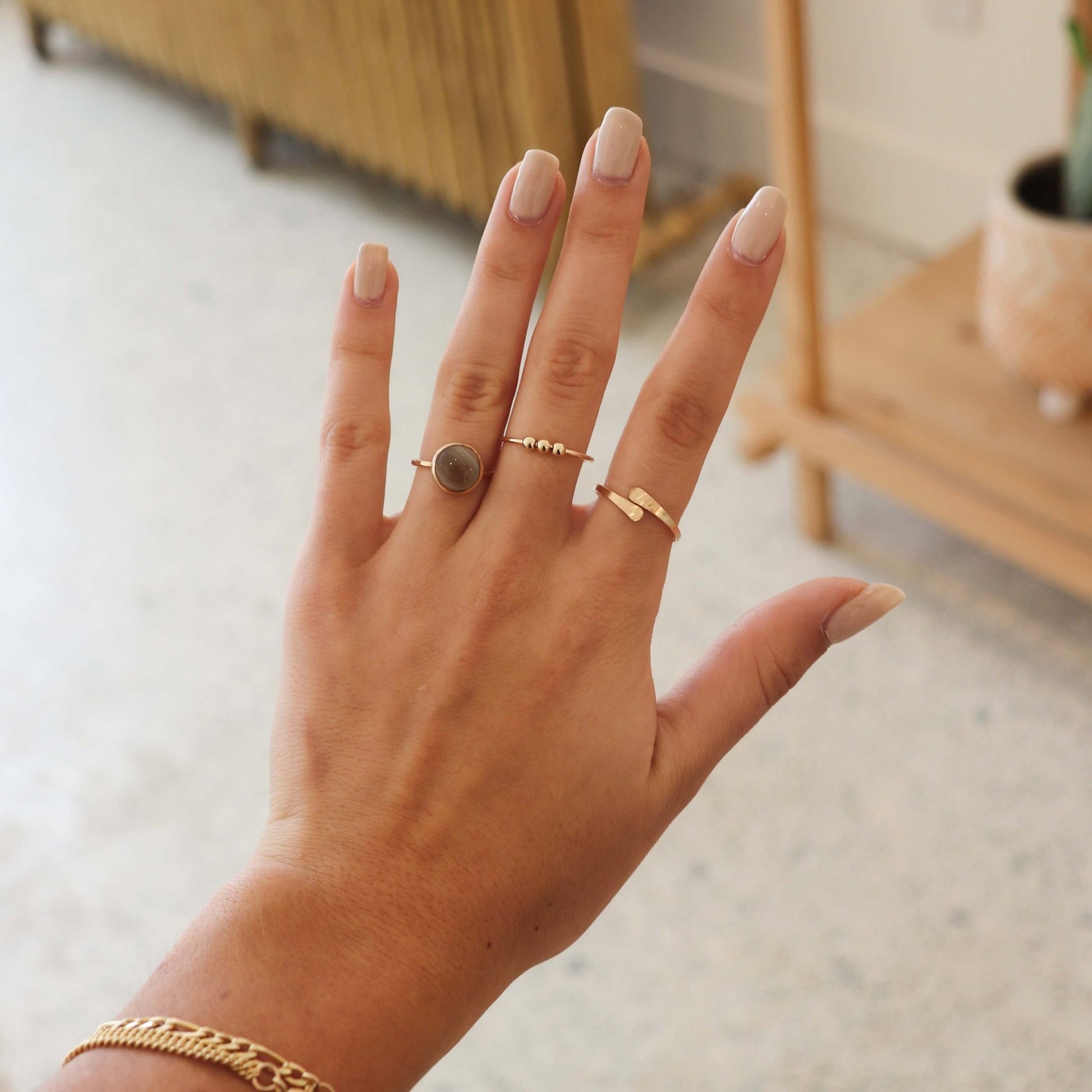 Gold Token Jewelry Meridian Fidget Ring worn with other rings, hand and wrist closeup.