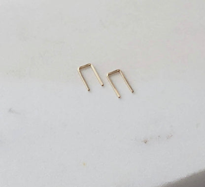 Token Jewelry Mini Staples earrings in gold on a white surface.