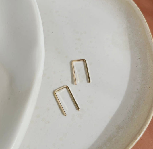 Token Jewelry Mini Staples earrings in gold displayed on a ceramic dish.